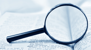 A magnifying glass resting on top of an open dictionary. 